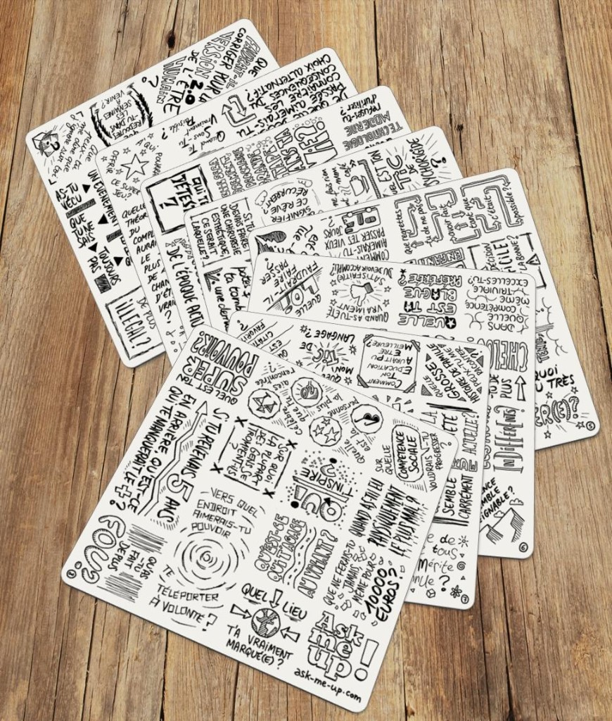 Les 8 sous-verres Ask Me Up! étalés sur une table en bois